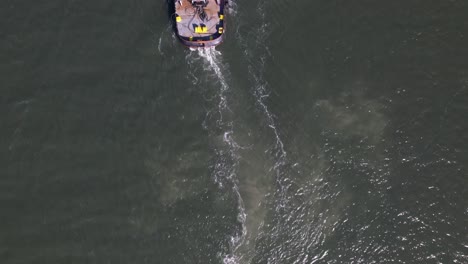 a top down, aerial view over a tugboat on a sunny day in the east rockaway inlet in queens, ny