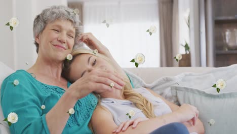 Animation-of-roses-over-happy-caucasian-mother-and-adult-daughter-hugging-on-sofa