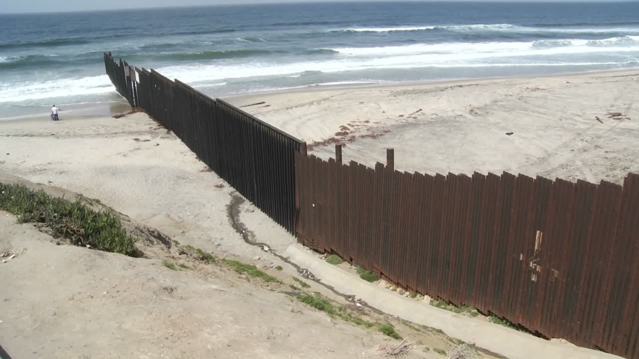 한 가족이 티후아나의 국경 벽 옆 해변에서 노는 모습이 보입니다.