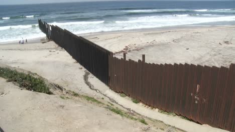 a family is seen playing on the beach next to the border wall in tijuana