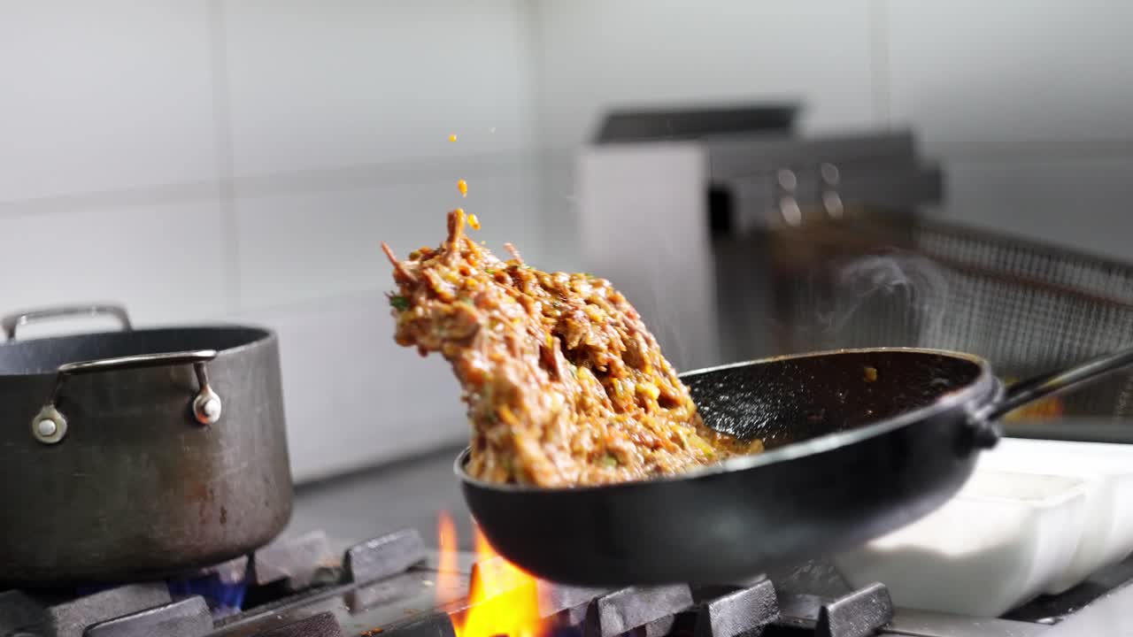 Slow motion view of a Beef stew being cooked and flying from a frying pan