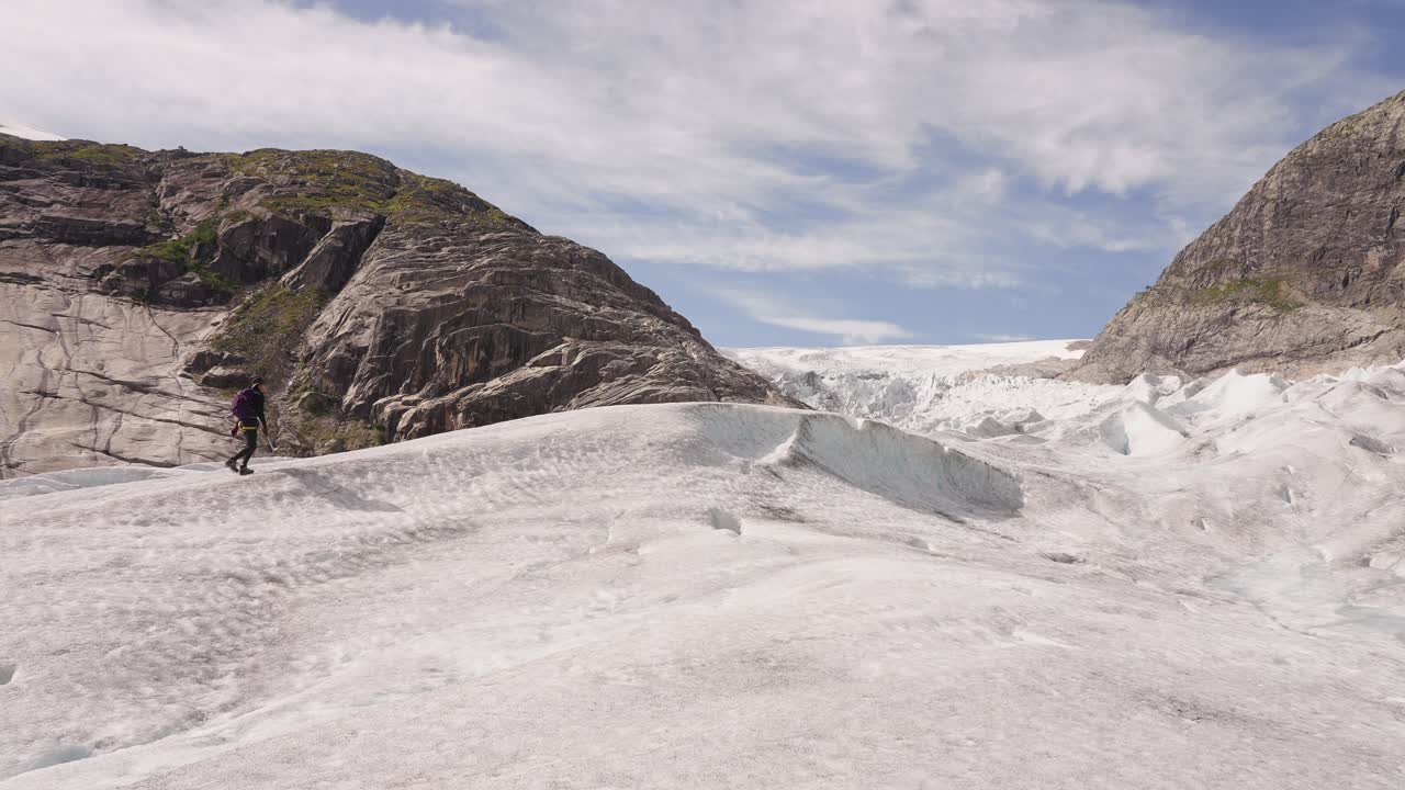 Hiker walking on a glacier in Norway under a bright sky, feeling free and peaceful