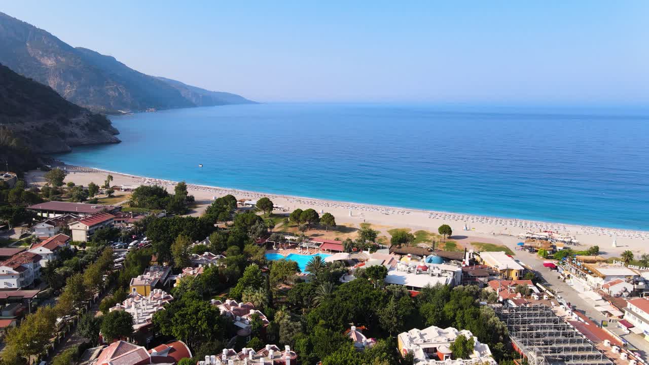 Türkiye'de Akdeniz, dağ manzaraları ve plaj fonunda bir sahil şehrinin panoramalarını çeken drone.