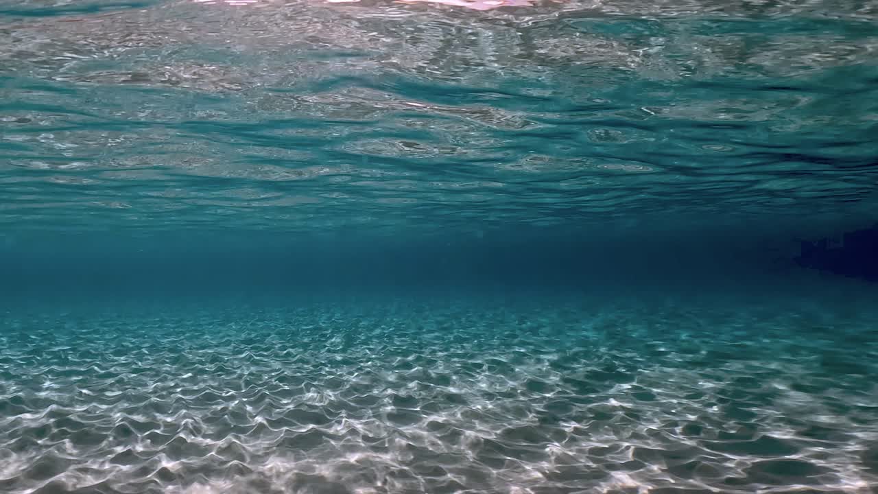 auténtica escena submarina de agua de mar tropical turquesa cristalina con superficie ondulada y reflejos en el fondo marino con fondo azul