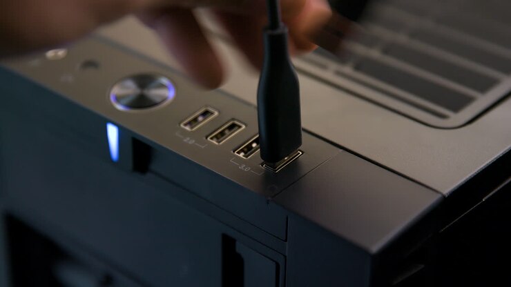 Uomo scollega diversi cavi USB da un computer desktop.