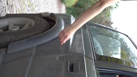 lady with soft, fair skin, natural nails, closes suv car door in nature, verticle