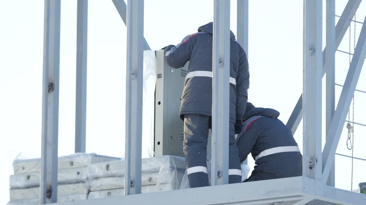 Workers Installing Equipment on a Tower in Winter