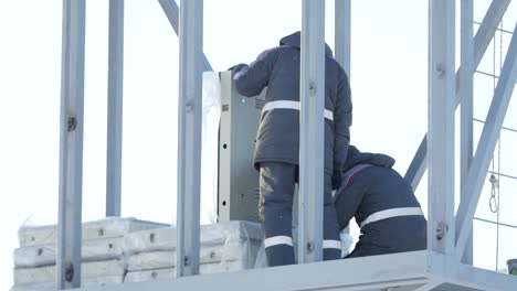 trabajadores que instalan equipos en una torre en invierno