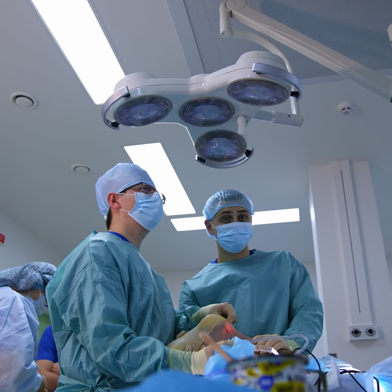 Surgical procedure in modern clinic. Medical specialists perform an operation in hospital. Doctor and assistant conduct a surgery with surgical equipment