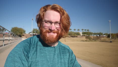 un hombre pelirrojo sonríe sentado en un parque en gilbert, arizona.