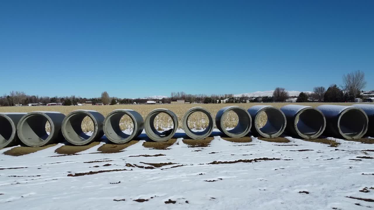 toma de drones en movimiento de tubos de hormigón en un campo de trigo cubierto de nieve