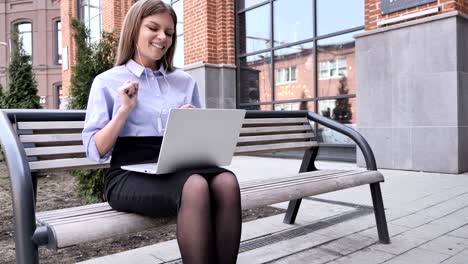 woman listening music and enjoying outside office building, laptop