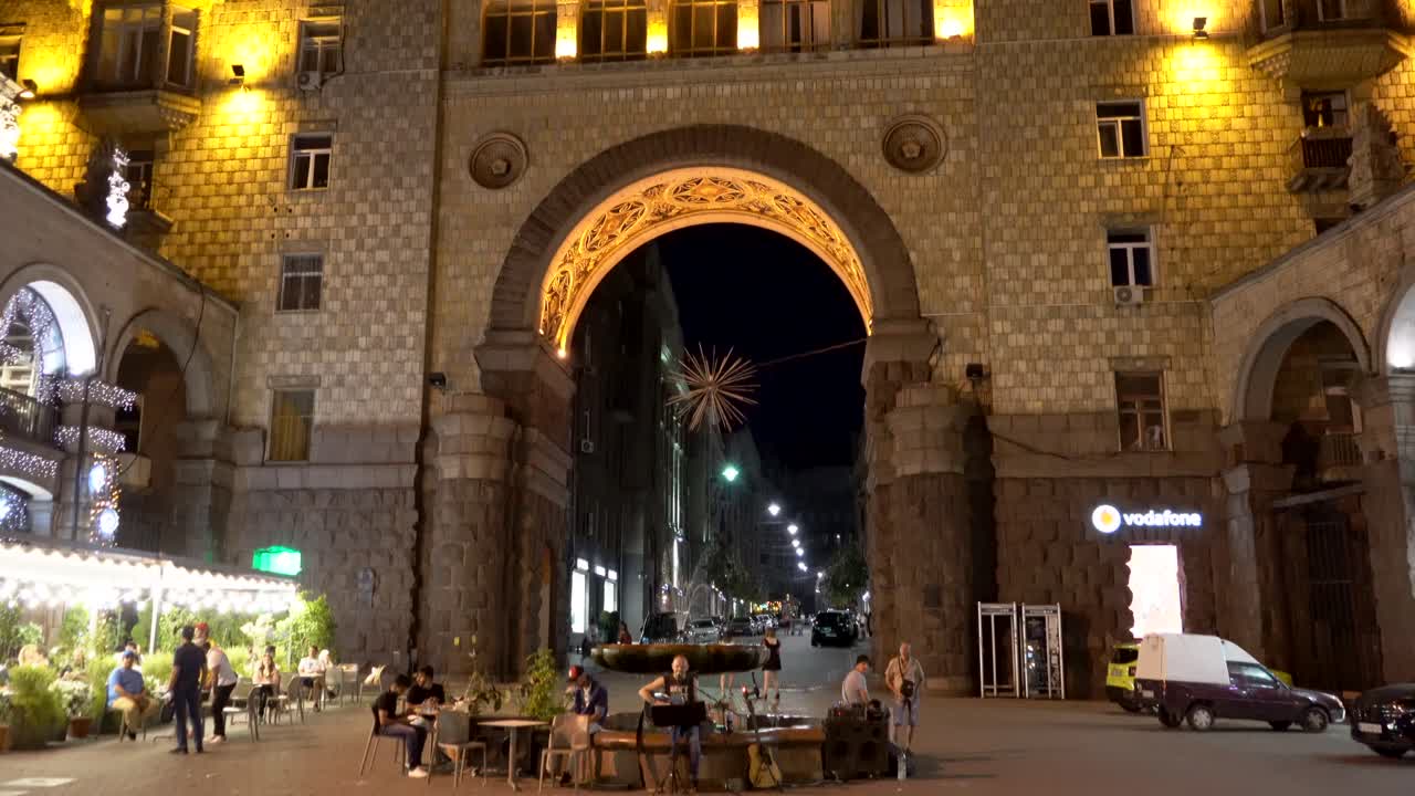 Ukraine,Kyiv,Khreschatyk Street,before the war,people enjoying themselves at the cafe's and the Street Musicians playing by the fountain near the street in front of an illuminated historical building