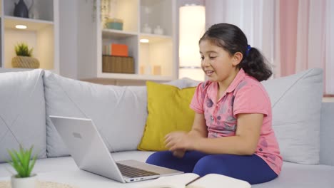 la niña mira la computadora portátil y se alegra.