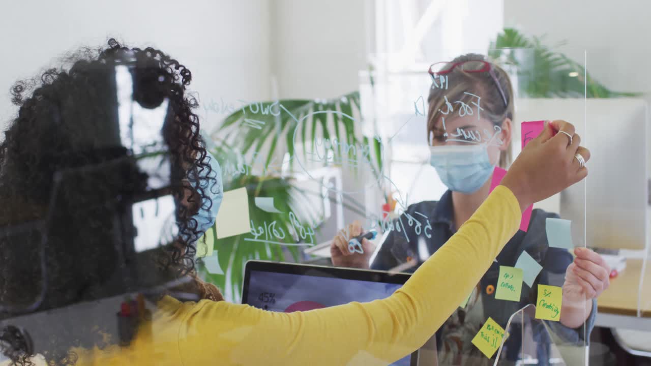 사무실 의 책상 에 있는 유리 판 에 글 을 쓰는 얼굴 마스크 를 착용 한 여자