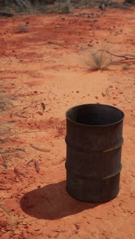 un barril oxidado sentado en un desierto de tierra roja