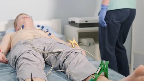 cardiac examination in a hospital with a professional cardiograph. the patient lies on a bed with connected sensors.