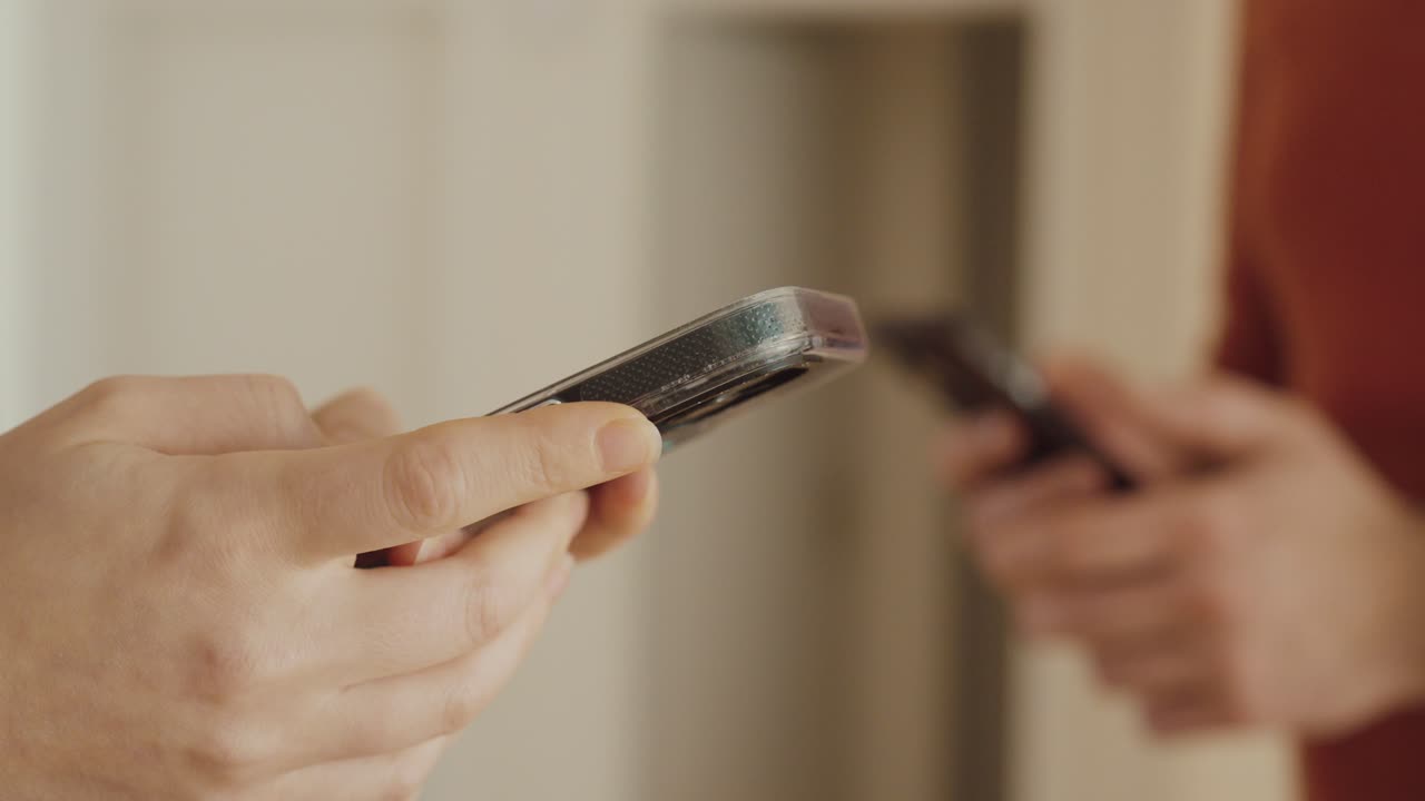 Primo piano di due persone che tengono in mano degli smartphone e digitano: concetto di comunicazione digitale, dipendenza dai social media o moderna tecnologia IA