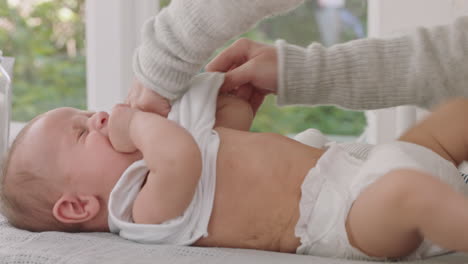 happy mother with baby dressing beautiful toddler caring for infant gentle mom enjoying motherhood nurturing her child at home