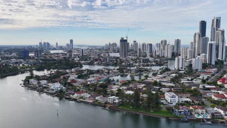 high-resolution drone footage pans over gold coast, australia, capturing modern skyscrapers, residential areas, and river under bright, partly cloudy daylight