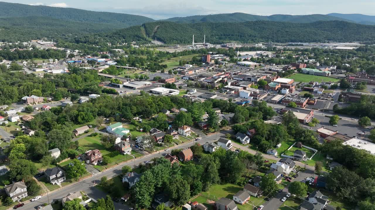 Colonial and Victorian houses in suburb of downtown during sunny day. Aerial wide shot. Peaceful neighborhood with well-kept yards in waynesboro, Virginia. Green mountains in distance