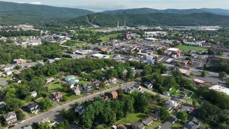 colonial and victorian houses in suburb of downtown during sunny day. aerial wide shot. peaceful neighborhood with well-kept yards in waynesboro, virginia. green mountains in distance