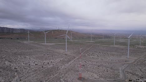 Aerial-footage-of-a-wind-farm-in-the-Palm-Springs-desert-on-a-cloudy-day,-slow-backwards-dolly-shot