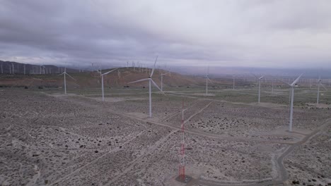 Imágenes-Aéreas-De-Un-Parque-Eólico-En-El-Desierto-De-Palm-Springs-En-Un-Día-Nublado,-Lenta-Toma-De-Carro-Hacia-Atrás