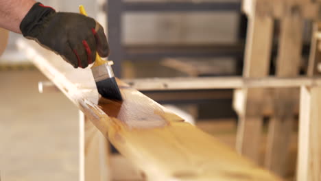 carpenter applying colorless protective coat on termo pine material