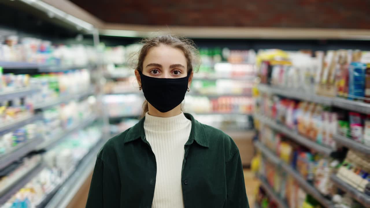 여성 쇼핑객이 코로나바이러스 전염병 기간 동안 구매를 하고, 보호 마스크를 입고 가게를 돌아다니고 있습니다.