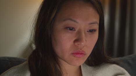 close up of stressed anxious woman spending evening at home sitting on sofa reacting to internet or social media news or financial story on laptop