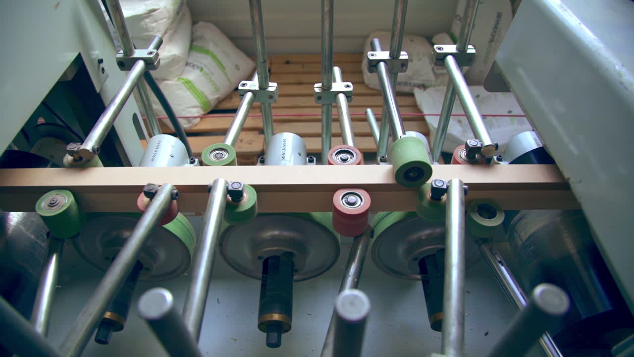 Conveyor line with multiple rollers. Timber bar is moved along the spinning shafts for following processing.