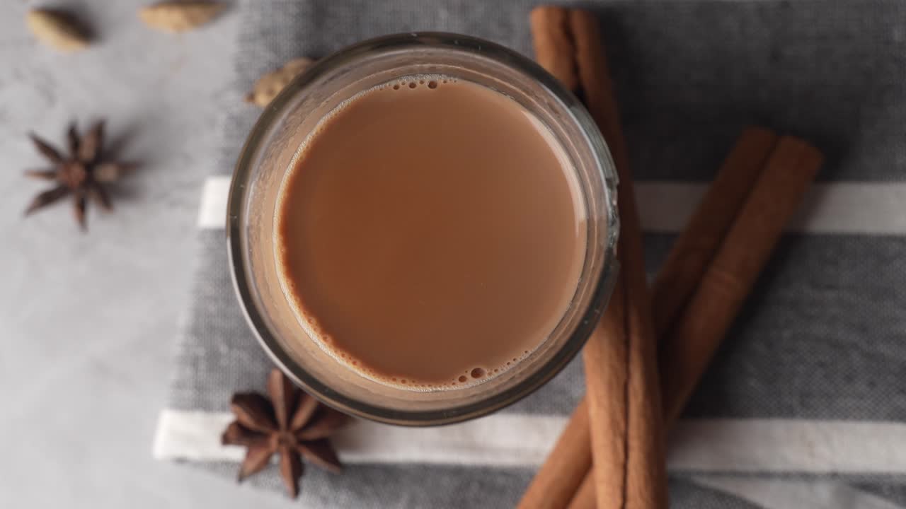Chai indiano servito in tazze di vetro, preparato in una teiera di metallo con masala aromatici