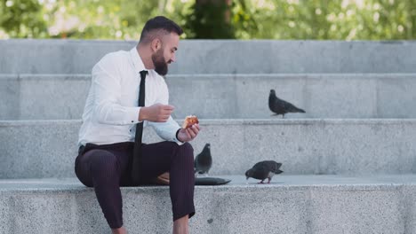 businessman having lunch outdoors with pigeons