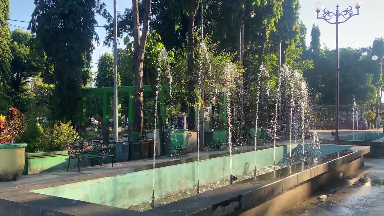 Fuente de agua chorreando en un parque público verde