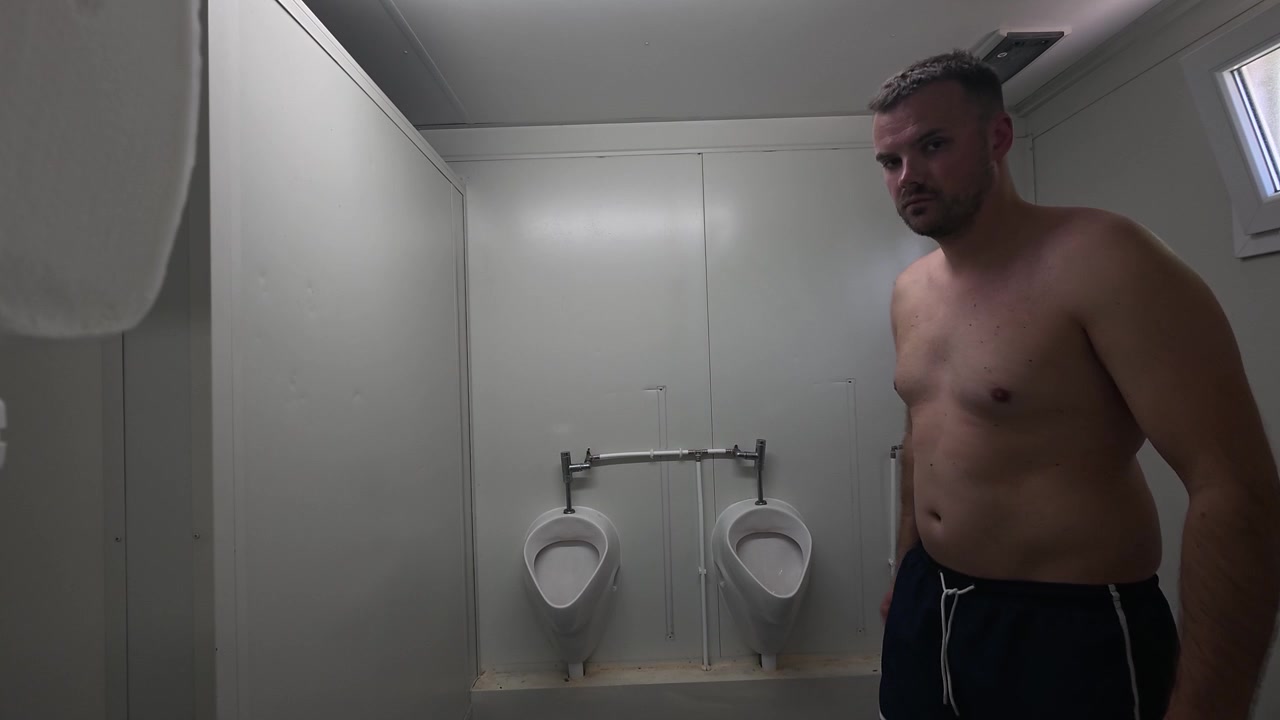Man standing inside a public swimming pool restroom facility. Hygiene, sanitation, public amenities, and recreational infrastructure concept in a sports and leisure environment.