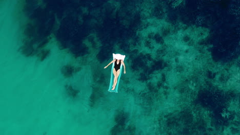 woman relaxing on inflatable raft in turquoise water