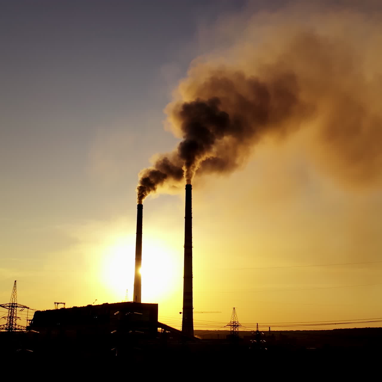Black factory background. Metallurgical plant with two pipes in the evening. Dirty emissions pouring out of pipes at sunset.