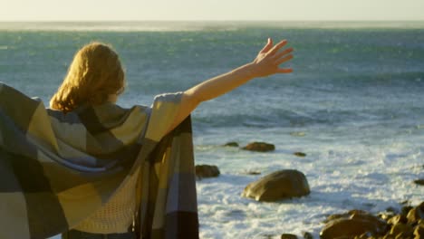 mujer de pie con los brazos extendidos cerca de un mar 4k