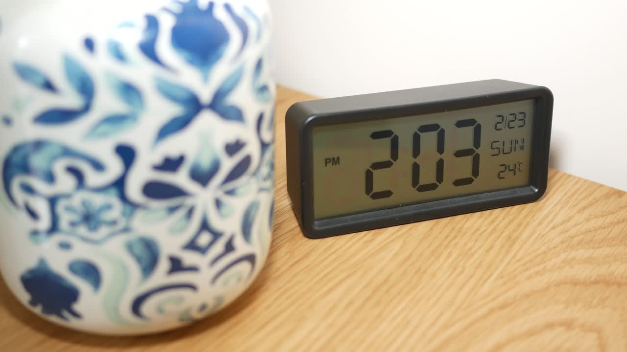 reloj digital en mesa de madera con taza decorativa