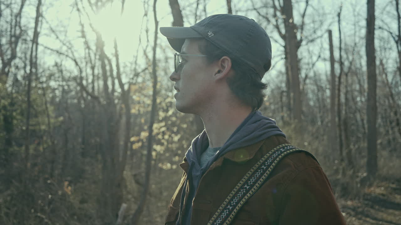 un joven fotógrafo mira hacia el bosque al sol
