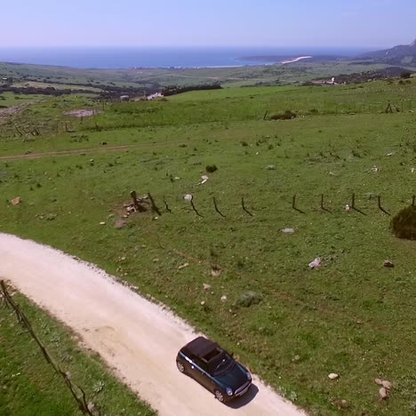 Aerial-View-Of-Driving-Car-On-Hilly-Terrain