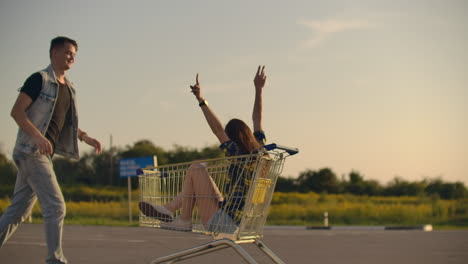 Young-friends-having-fun-on-shopping-trolleys.-Multiethnic-young-people-racing-on-shopping-cart.-slow-motion