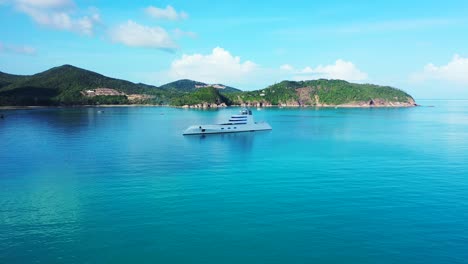 luxurious yacht floating on blue azure sea water near coastline of tropical island with lush vegetation on a sunny summer day in thailand