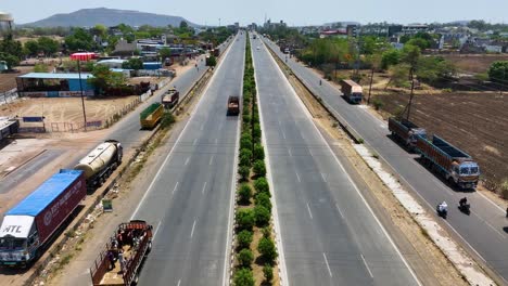 aerial dolly shot of large trucks traveling along a highway in maharashtra, india