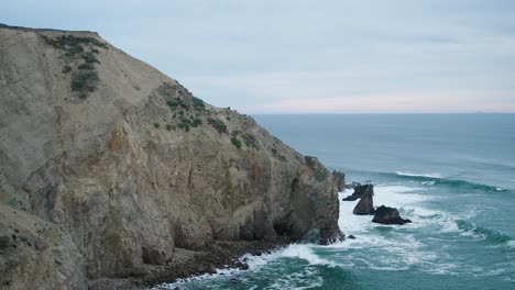 overview shot of waves hitting against a steep cliff outside of san francisco