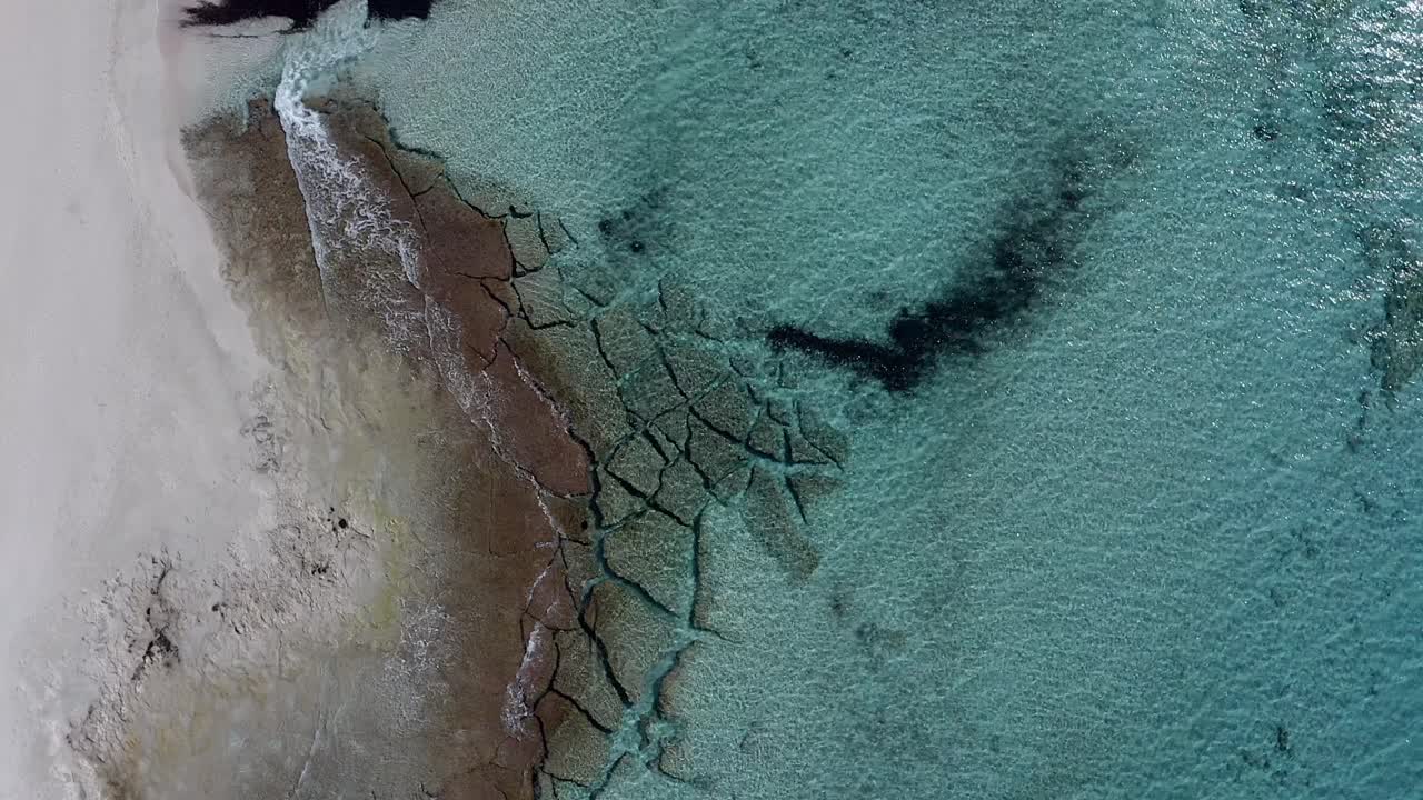 Drone spinning around waves along beach in Spain