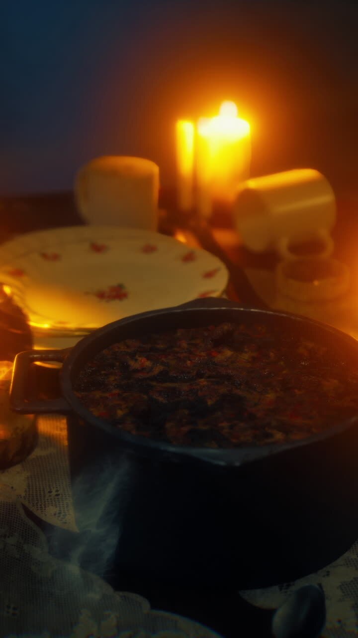 A pot of food steaming on a table with candles lit