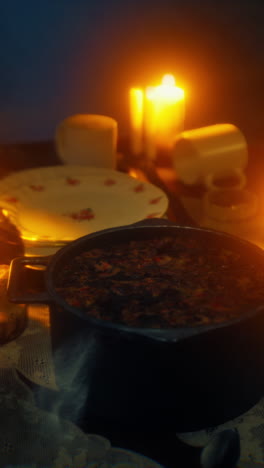 a pot of food steaming on a table with candles lit