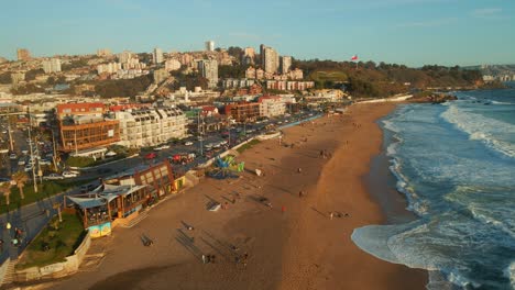 Aerial-view-flying-over-Reñaca-golden-Chile-scenic-sandy-beach-waterfront-above-ocean-waves